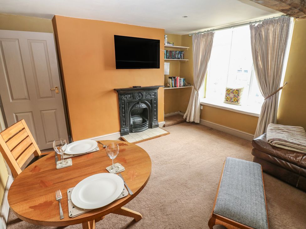A living room with a dining table and fireplace at Ewe Cottage in Masham
