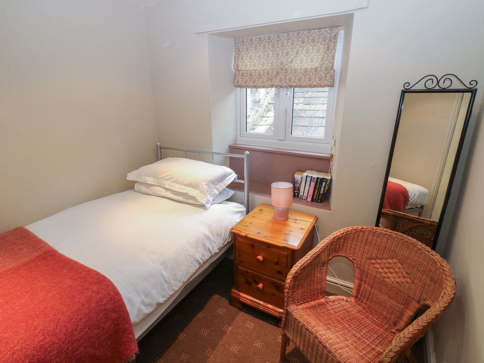 A bedroom with a bed and a chair at Ewe Cottage in Masham