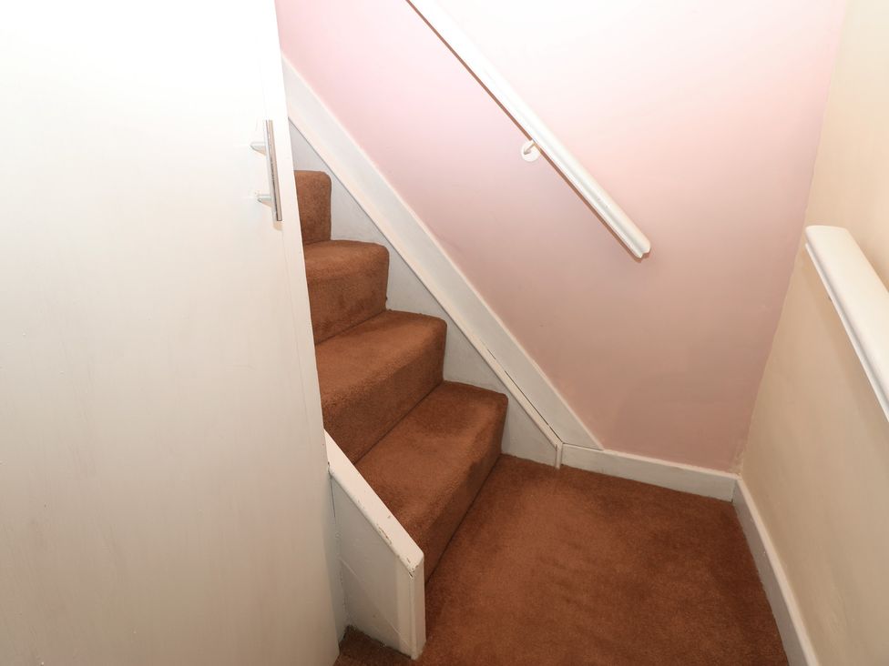 A staircase with a handrail and a door near Ewe Cottage in Masham