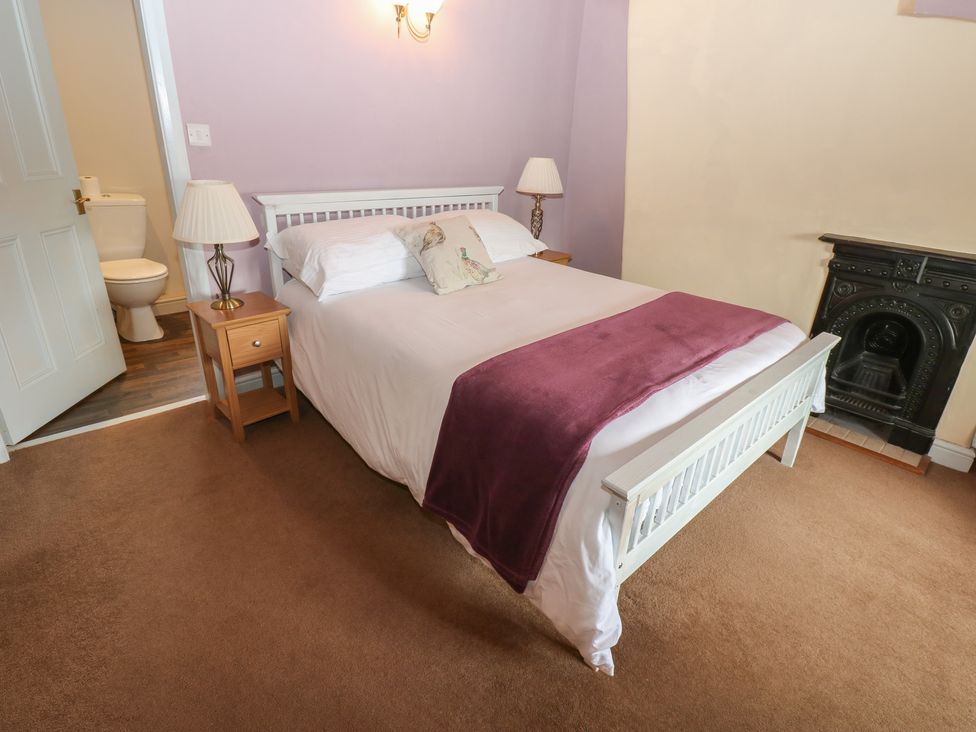 A bedroom with a bed and nightstand at Ewe Cottage in Masham