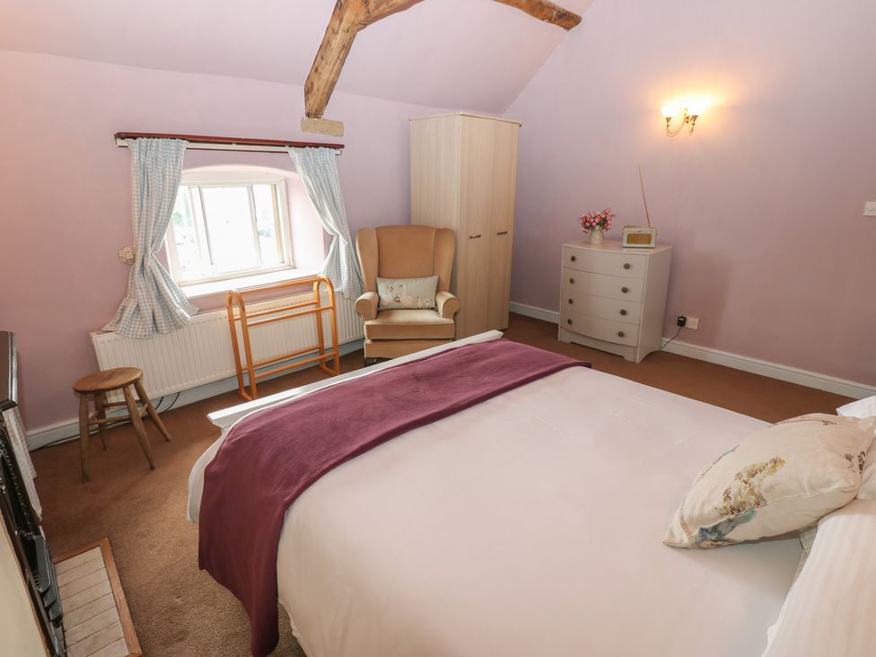 A bedroom with a bed and an armchair at Ewe Cottage in Masham