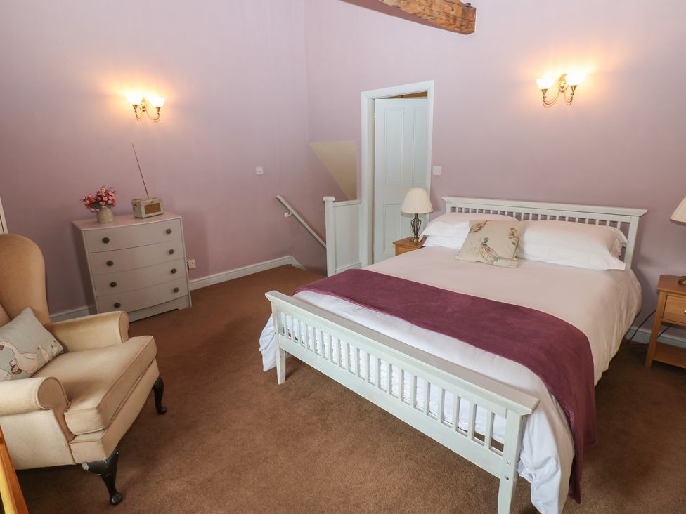 A bedroom with a bed and chair at Ewe Cottage in Masham