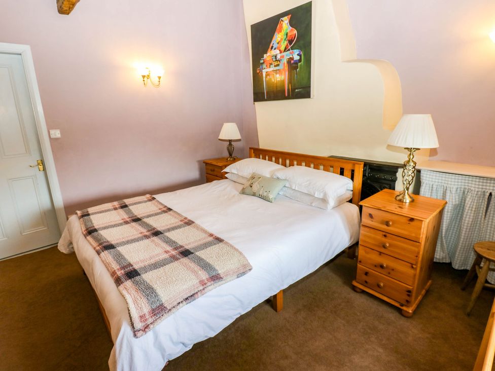 A bedroom with a bed and bedside tables at Ewe Cottage in Masham