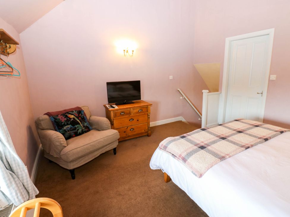 A bedroom with an armchair and television at Ewe Cottage in Masham