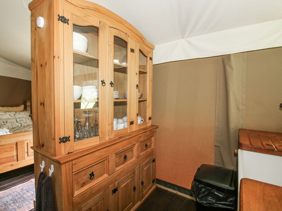 A hutch with dishes and glasses in a tent at Hedgerow in Bewdley