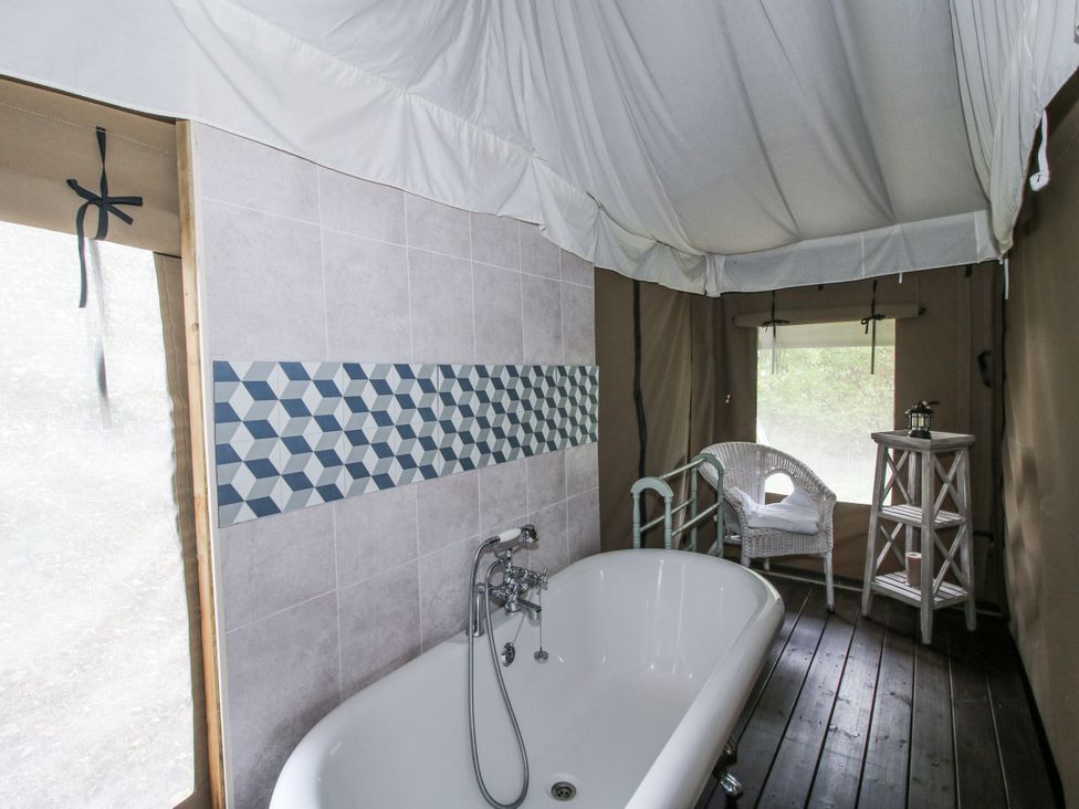 A bathroom with a bathtub and wooden table at Hedgerow in Bewdley