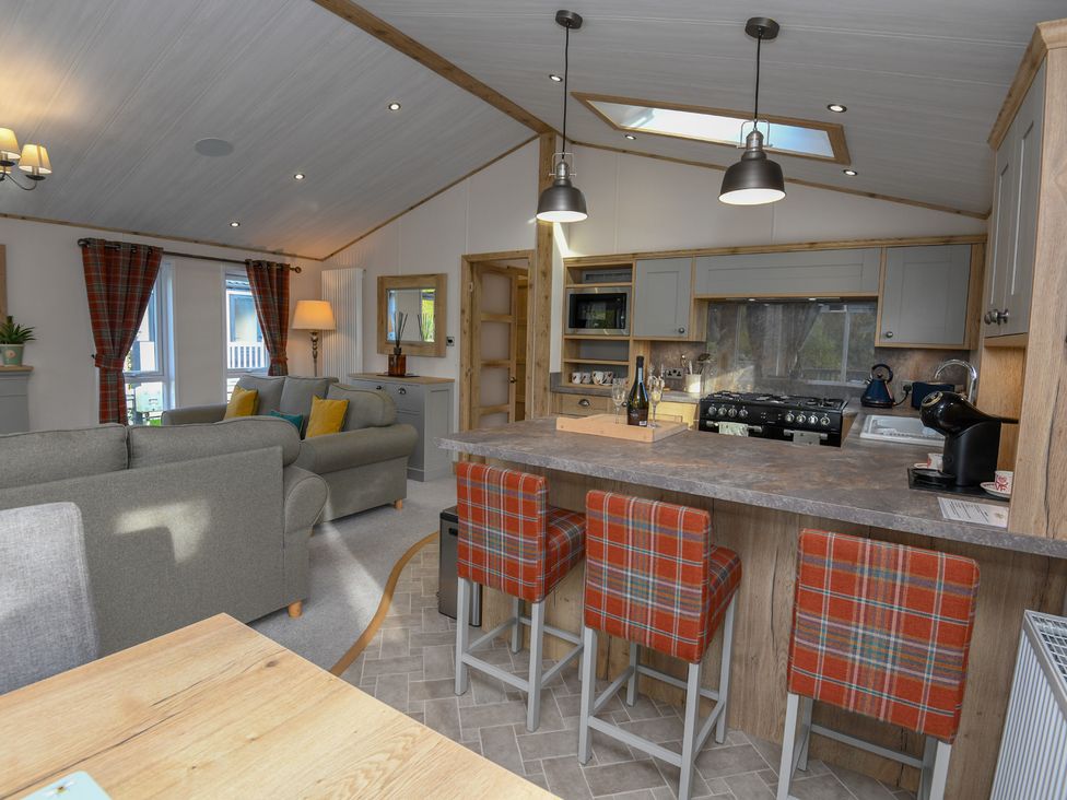 A kitchen with bar stools and sofa at Lakewood Retreat in Woodhall Spa