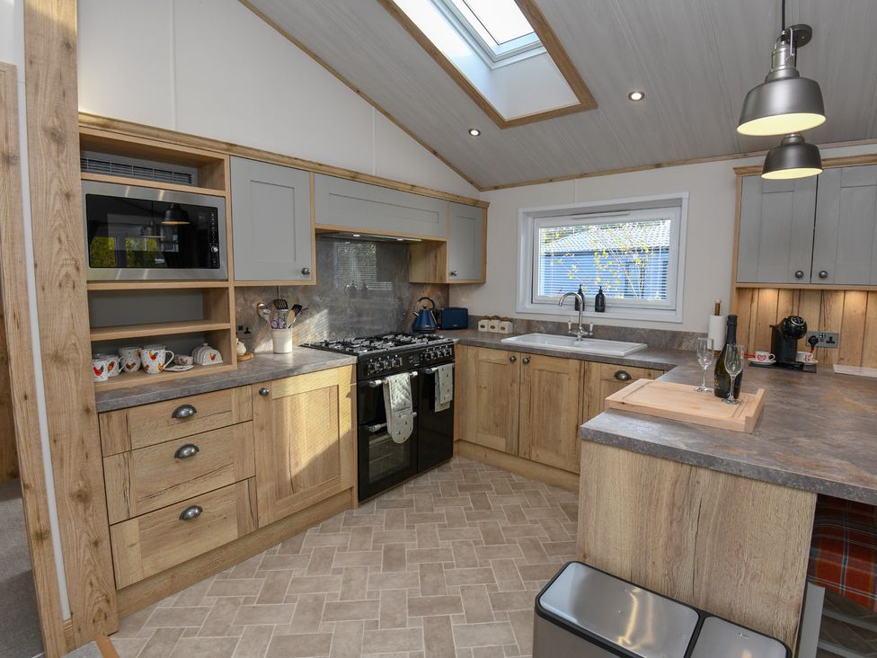 A kitchen with cabinets, a sink, and appliances at Lakewood Retreat in Woodhall Spa