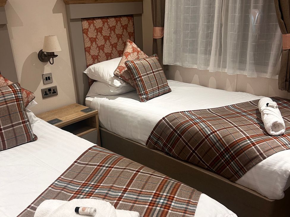 Two single beds with patterned bedding and pillows at Lakewood Retreat in Woodhall Spa