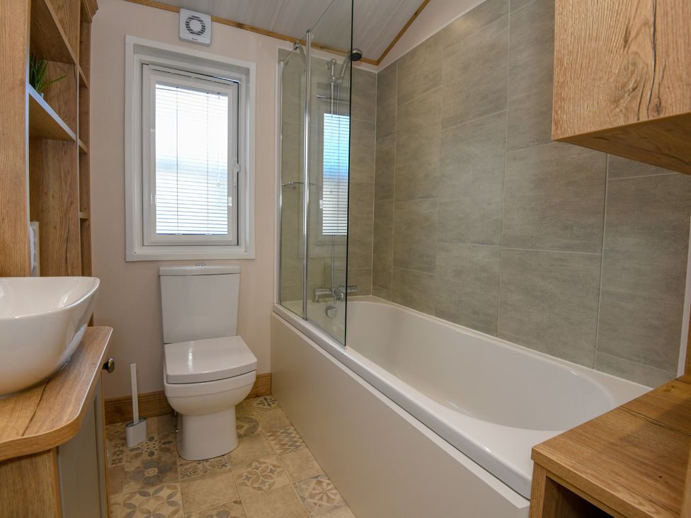 A bathroom with a bathtub, shower, sink and toilet at Lakewood Retreat in Woodhall Spa