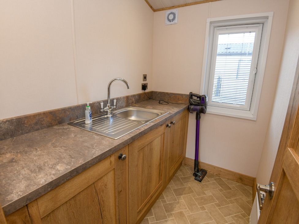 A utility room with a sink and storage cabinets at Lakewood Retreat in Woodhall Spa