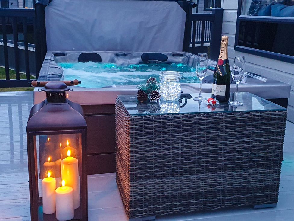 An outdoor area with a hot tub and drinks at Hotchkin Lodge in Woodhall Spa