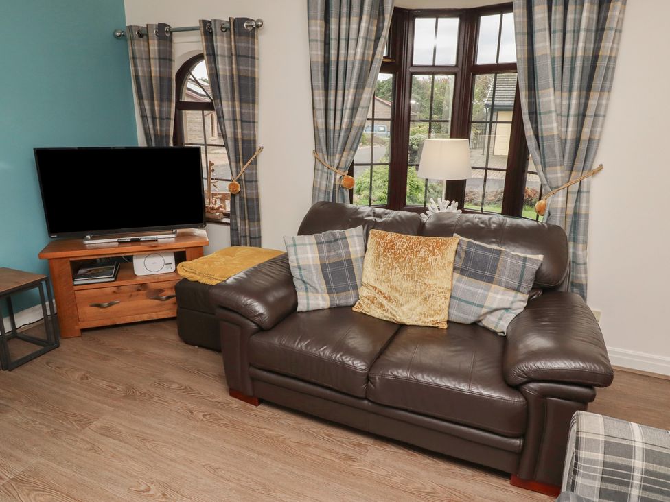 A living room with a sofa and television at Nobles Nook in Seahouses