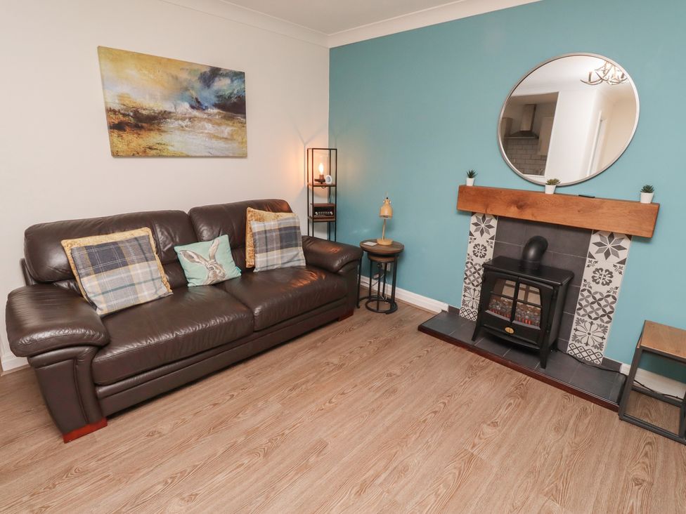 A living room with a sofa and fireplace at Nobles Nook in Seahouses