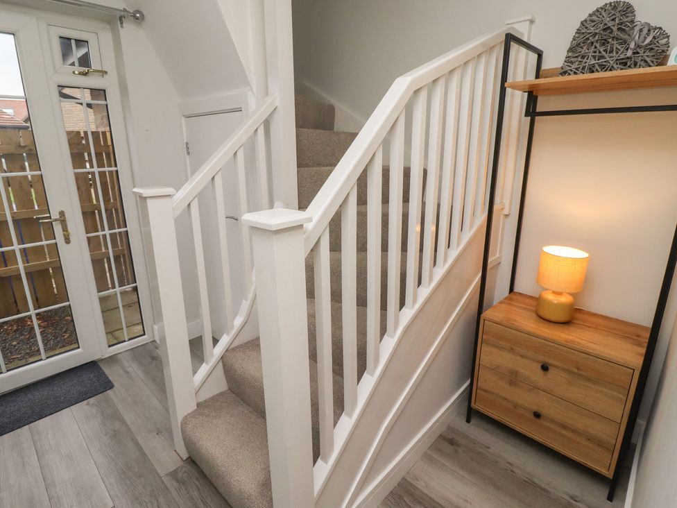 A hallway with a staircase and a console table at Nobles Nook in Seahouses