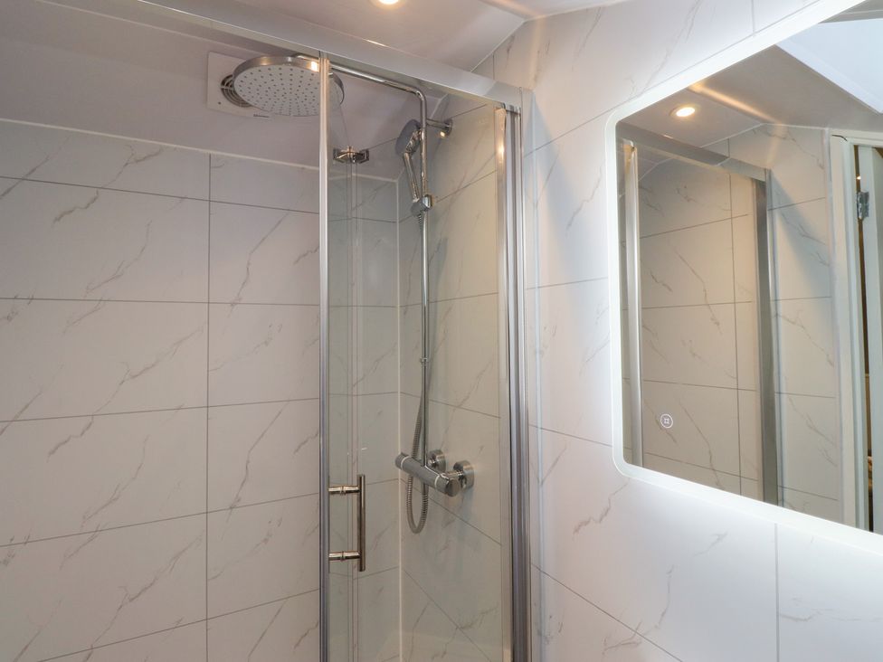 A bathroom with a shower and mirror at Nobles Nook in Seahouses