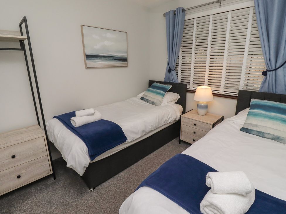 A bedroom with two beds and a nightstand at Nobles Nook in Seahouses
