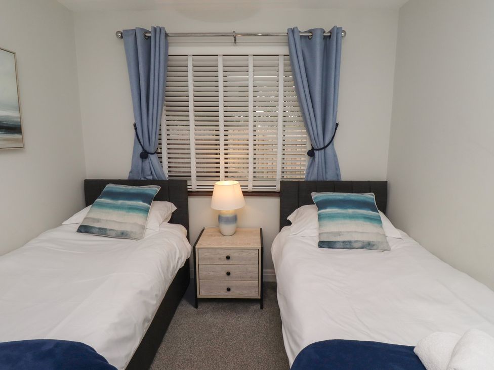 A bedroom with two single beds and a nightstand at Nobles Nook in Seahouses