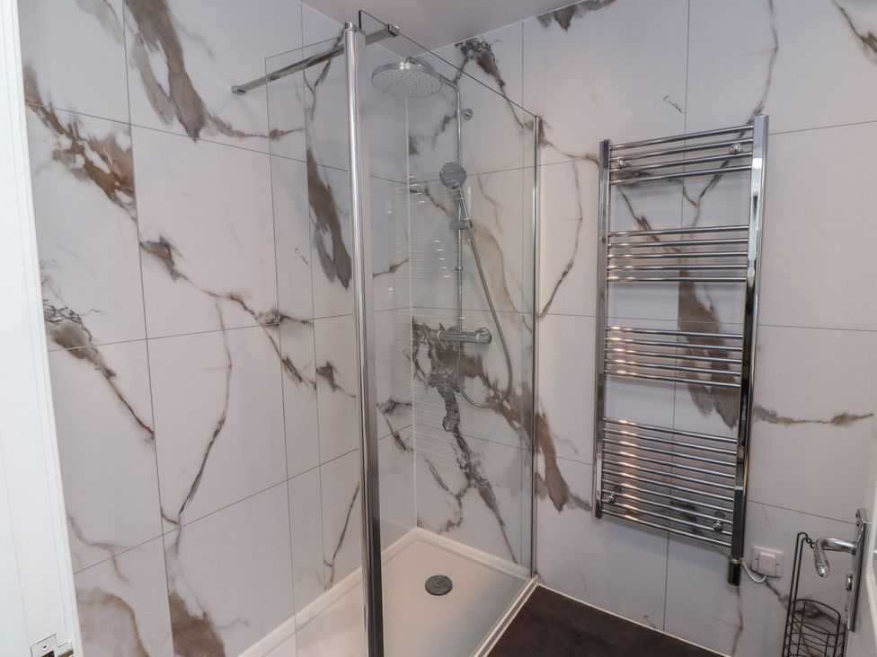 A shower area with glass door and towel rail at Nobles Nook in Seahouses