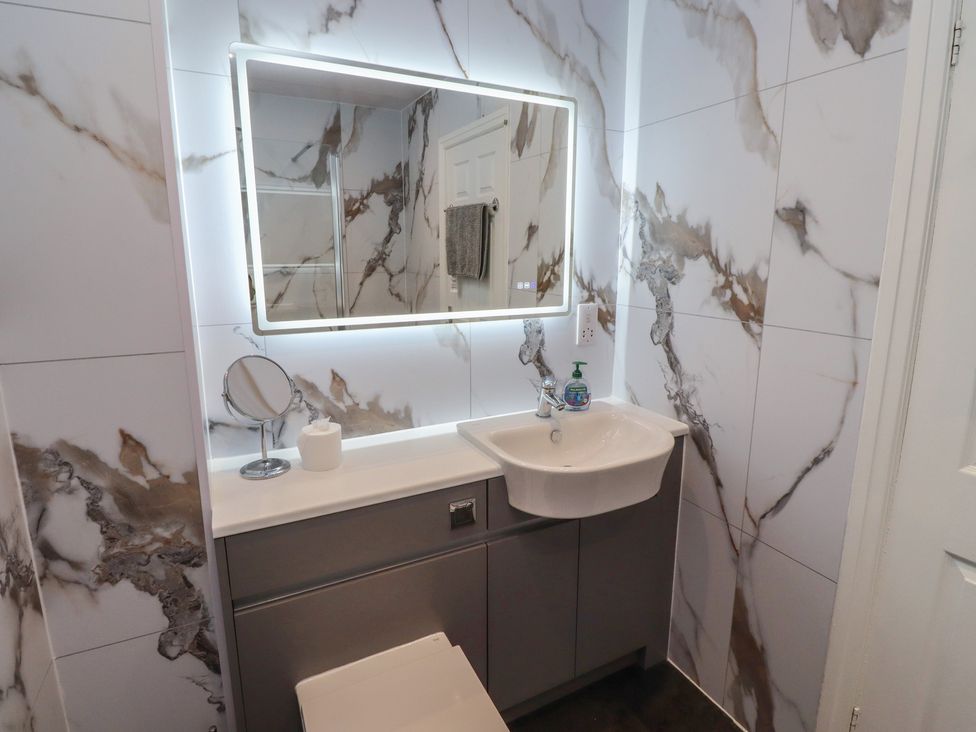 A sink and mirror in a bathroom at Nobles Nook in Seahouses