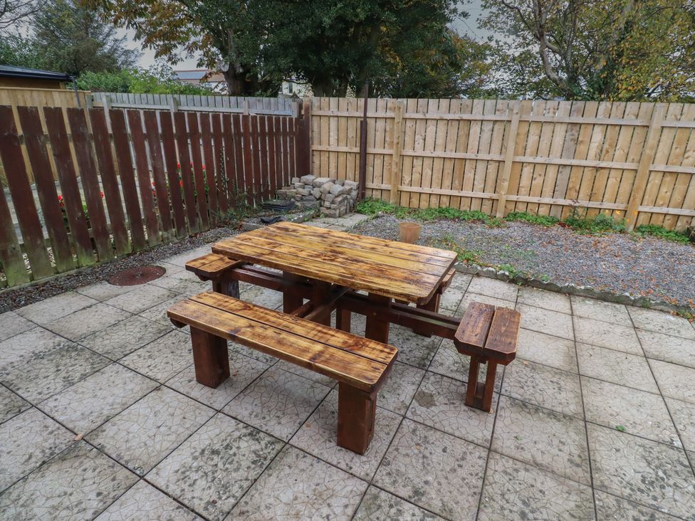 A garden with a wooden table and benches at Nobles Nook in Seahouses