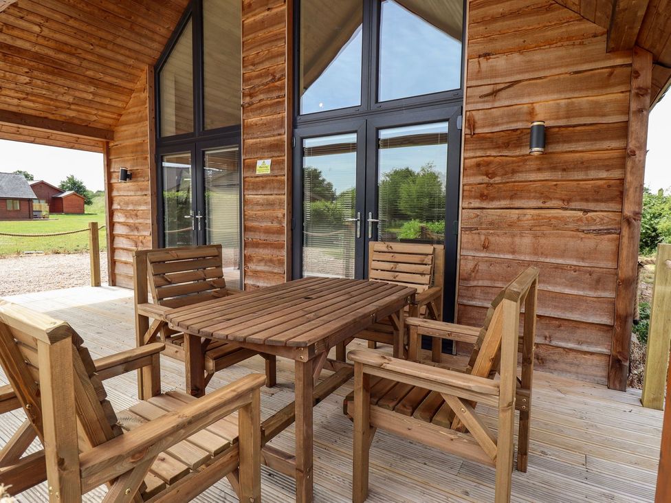 An outdoor seating area with a wooden table and chairs at Lodge 12 in South Hykeham