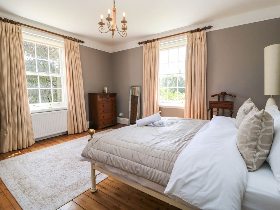 A bedroom with a bed and windows at The Mount in Chippenham