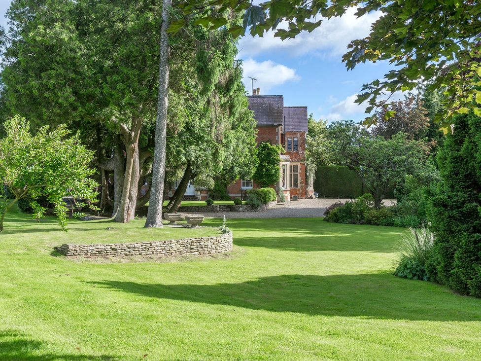 A garden with trees and a stone wall at The Mount Private Estate Upper Seagry