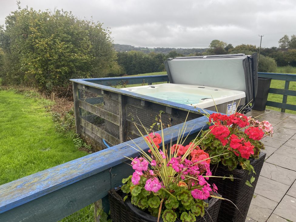 A hot tub with flower pots on a deck at The Cow Shed in Bishopswood