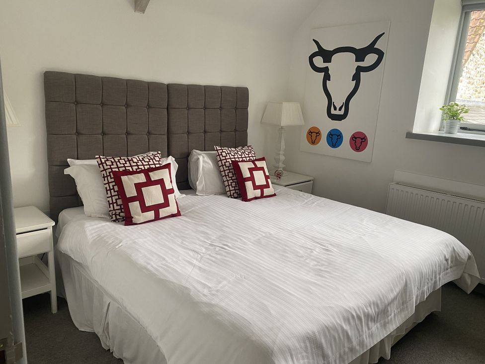 A bedroom with a bed and bedside table at The Cow Shed in Bishopswood