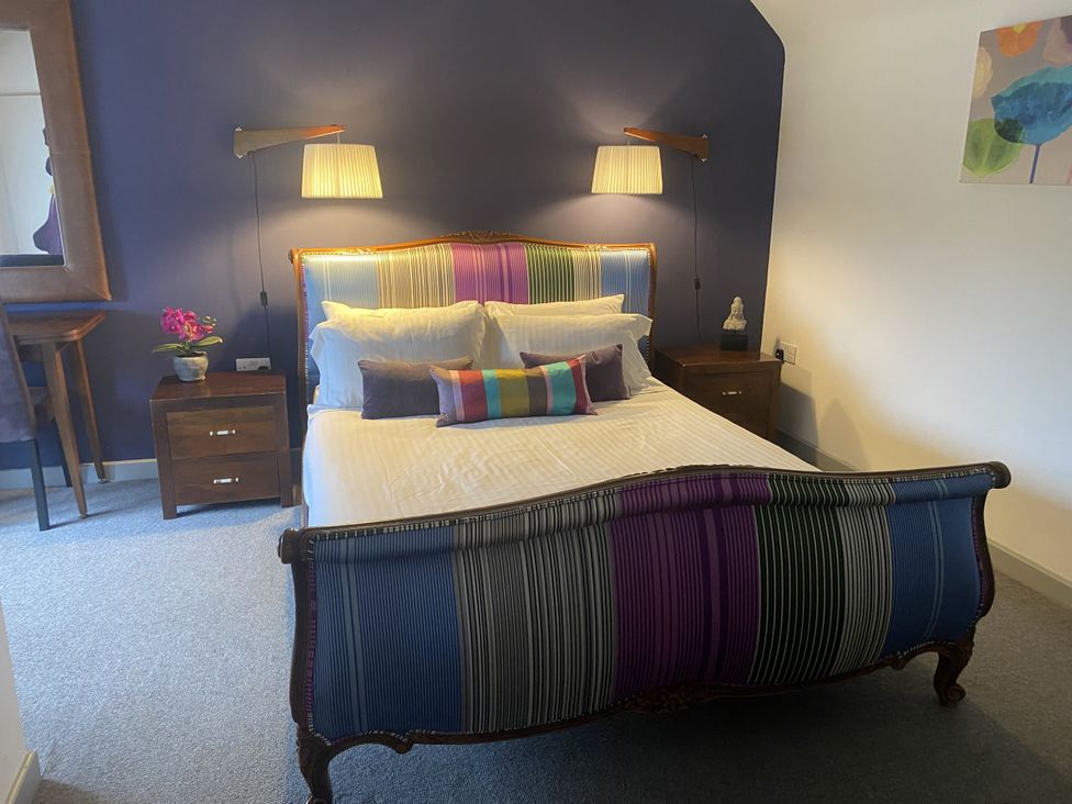 A bedroom with a bed and nightstands at The Cow Shed in Bishopswood