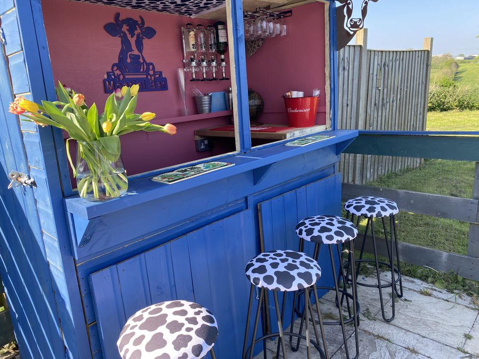An outdoor bar with stools and flowers at The Cow Shed in Bishopswood