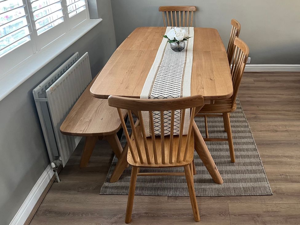 A dining table with chairs and a vase at Shepherd's Lodge in Skipton