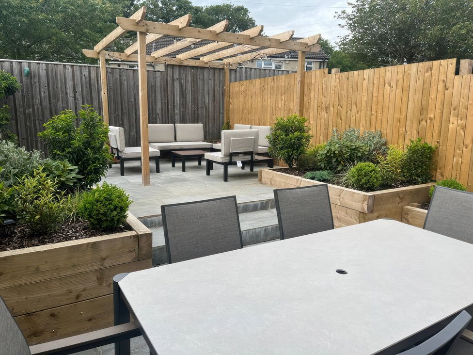 An outdoor seating area with a wooden pergola and plants at Shepherd's Lodge in Skipton