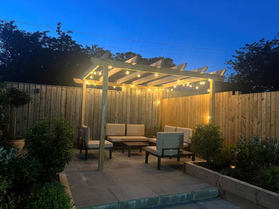 A garden with an outdoor seating area and a pergola at Shepherd's Lodge in Skipton