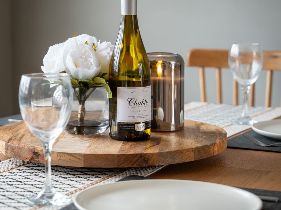 A wine bottle and flowers on a wooden table in the dining room at Shepherd's Lodge Skipton