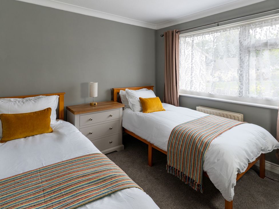 A bedroom with two beds and a nightstand at Shepherd's Lodge in Skipton