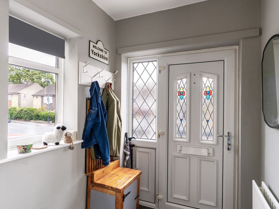 A hallway with a door and coat hooks at Shepherd's Lodge in Skipton