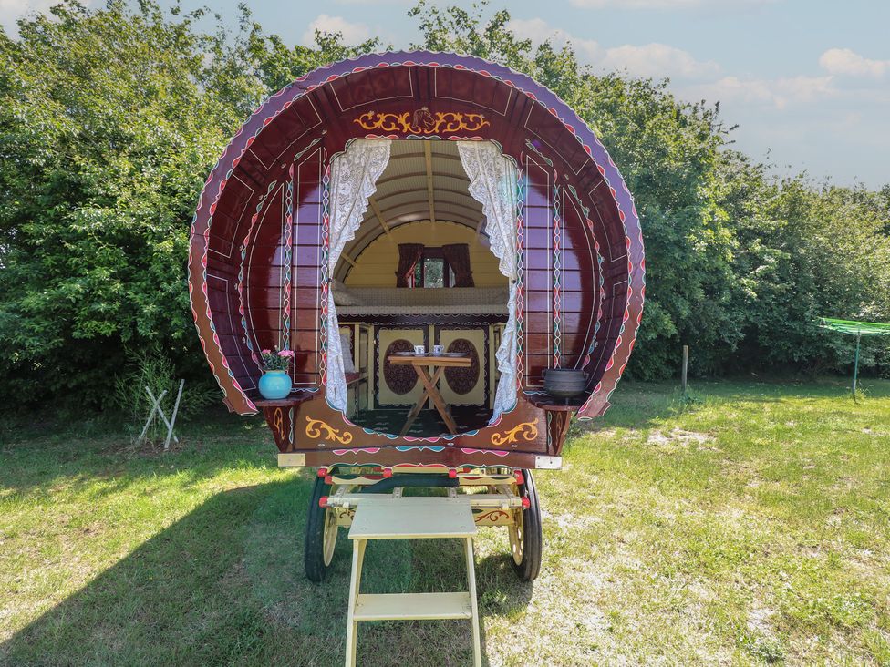 A gypsy caravan with a table and chairs outside at The Bowtop Gypsy Caravan in Eye