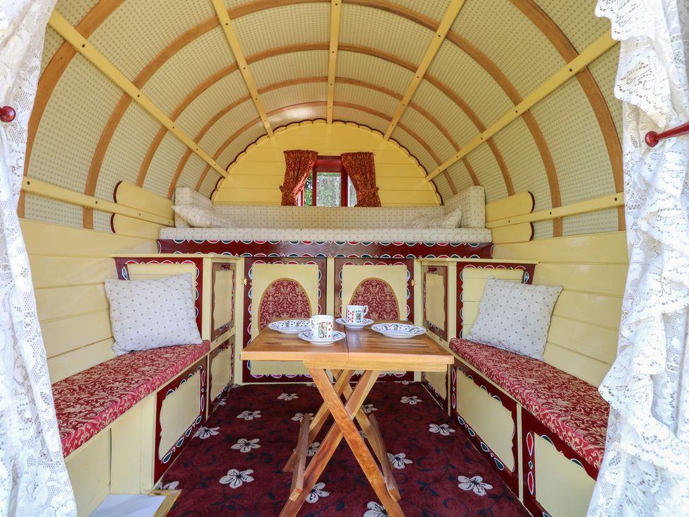 A main room with a table and seating at The Bowtop Gypsy Caravan in Eye