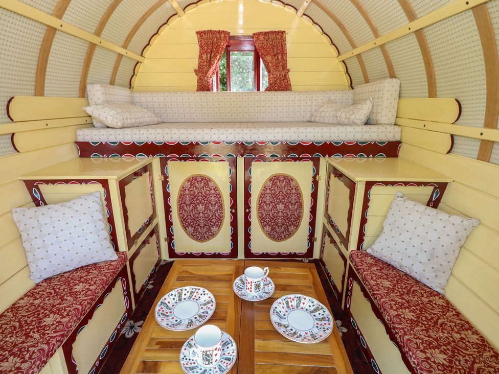 A living room with cushions and a table at The Bowtop Gypsy Caravan in Eye