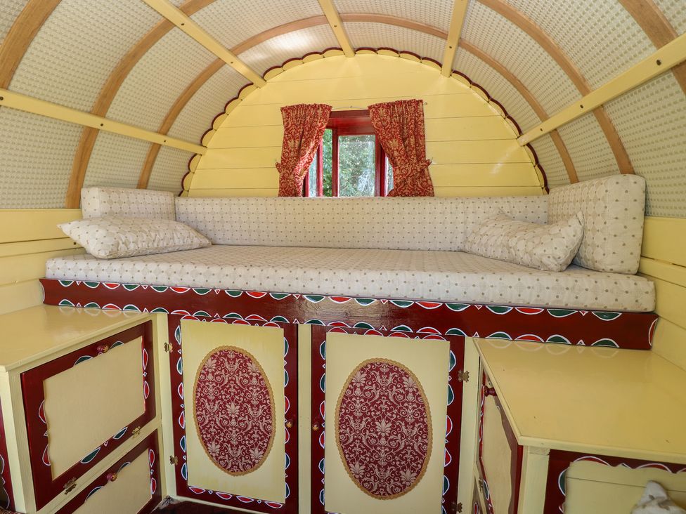 A sleeping area with a bed and cabinets at The Bowtop Gypsy Caravan in Eye