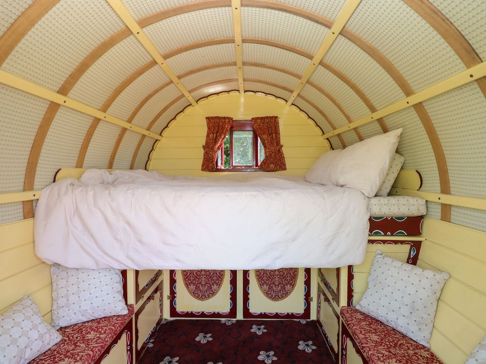A bedroom with a bed and cushions at The Bowtop Gypsy Caravan in Eye