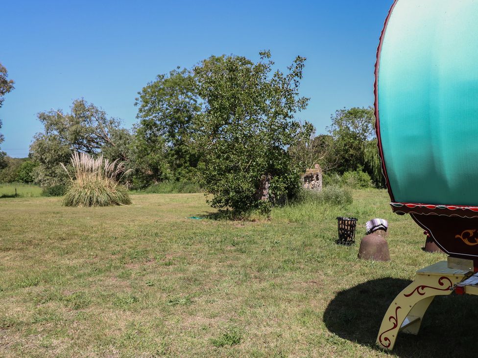 An outdoor area with a caravan and trees at The Bowtop Gypsy Caravan in Eye