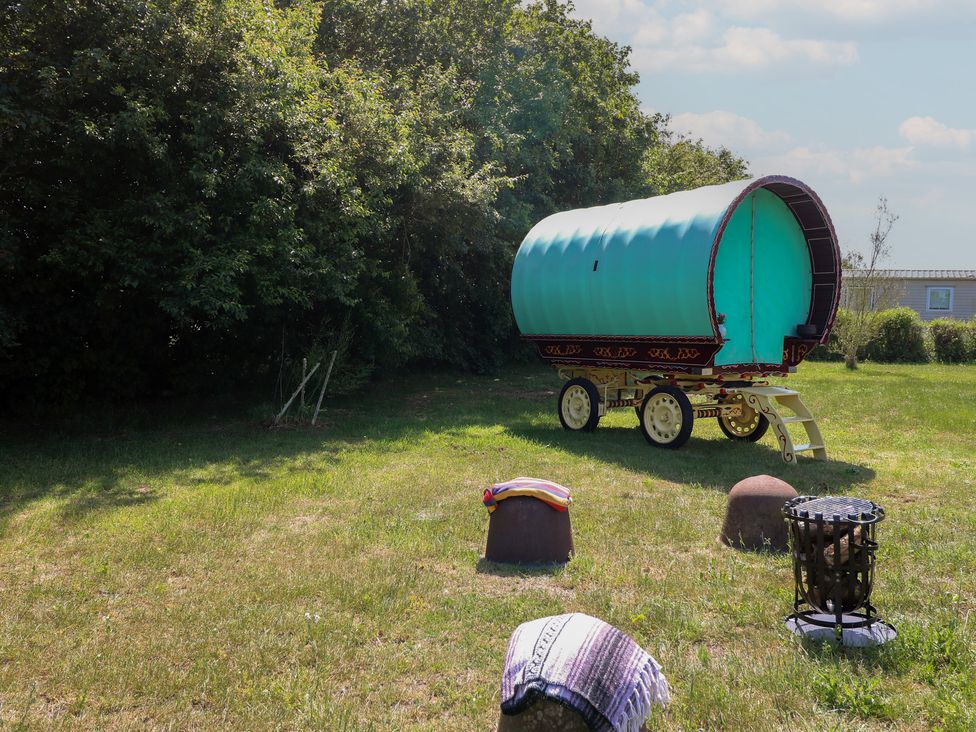 A caravan and firepit in a garden at The Bowtop Gypsy Caravan in Eye