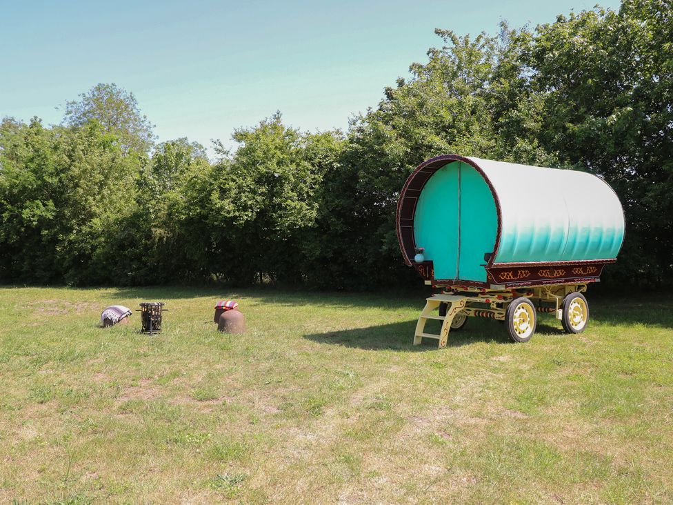A caravan on grass with a stool and pot at The Bowtop Gypsy Caravan in Eye