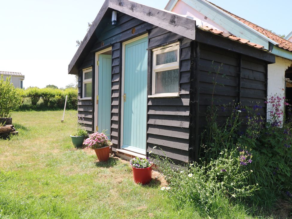 A shed with blue doors and flower planters at The Bowtop Gypsy Caravan in Eye