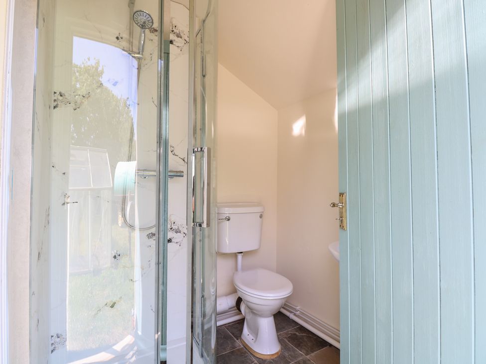 A bathroom with a shower, toilet, and hand sink at The Bowtop Gypsy Caravan in Eye