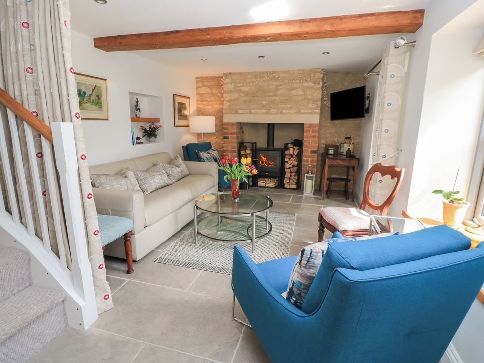 A living room with a sofa and fireplace at The Cottage in Ashton Keynes
