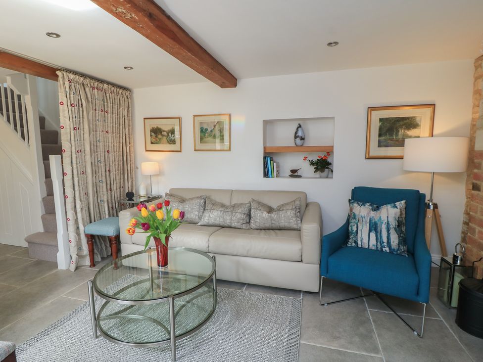 A living room with a sofa and armchair at The Cottage in Ashton Keynes